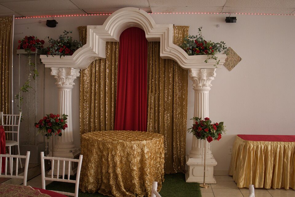 Fondo de arco con columnas blancas, lentejuelas doradas y rosas rojas