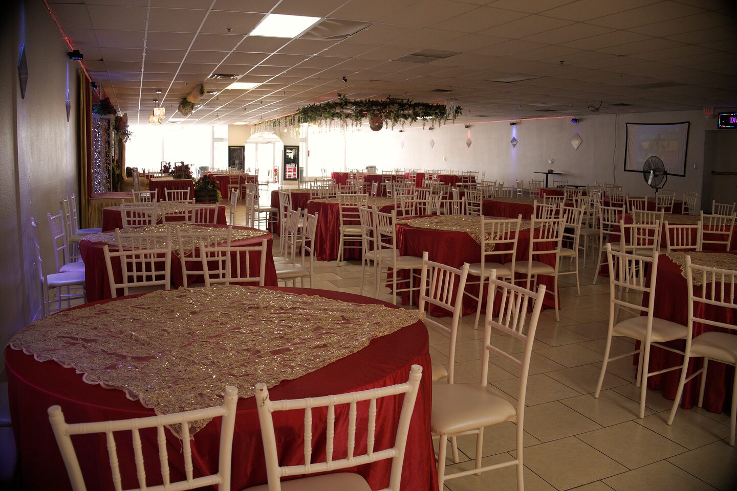 Salón de banquetes de Diana's con mesas en rojo y dorado y sillas Chiavari blancas